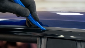 Audi S5 chrome delete. Progress photo of wrapping the top window trim. Using a squeegee to tuck the vinyl under the rubber. Photo two.