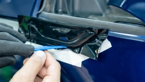 Audi S5 chrome delete. Progress photo of wrapping the front wing trim. Tucking the film around the edges using a squeegee. Photo two.