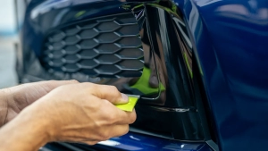 Audi S5 chrome delete. Progress photo of wrapping the front bumper lower trim. Tucking the vinyl around the edges using a squeegee. Photo one.