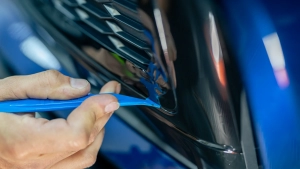 Audi S5 chrome delete. Progress photo of wrapping the front bumper lower trim. Tucking the vinyl around the edges using a squeegee. Photo two.