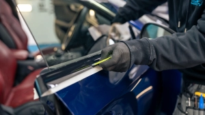 Audi S5 chrome delete. Progress photo of wrapping the front door window trim. Using the squeegee to tuck the vinyl under the trim. Photo one.