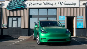 Tesla Model Y - Gloss Green Envy. Exterior photo of the front of the car.