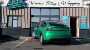 Tesla Model Y - Gloss Green Envy. Exterior photo of the rear of the car.